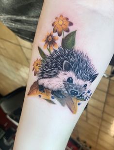 a small hedgehog with flowers on it's arm