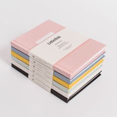 a stack of five notebooks sitting next to each other on top of a white surface