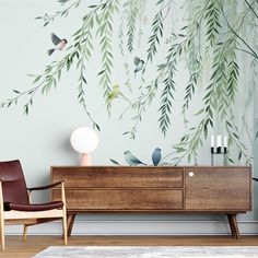 a living room with a wall painted with birds and branches on the wall next to a chair