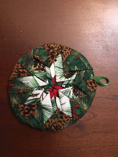 an ornament on a wooden table with pine cones and holly leaves, tied to it