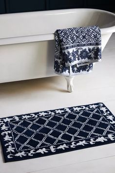 a bath tub sitting next to a blue and white rug