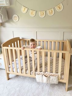 a baby is sitting in his crib and smiling at the camera while hanging decorations above him