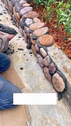 a man laying on the ground next to a wall made out of rocks and stones