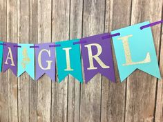 a purple and blue banner with the word girl hanging from it's side on a wooden fence