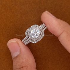 a close up of a person's hand holding a diamond ring