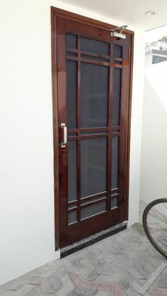 a bicycle is parked in front of a wooden door with glass panels on the side