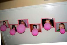 there are pink balloons hanging on the wall with pictures attached to them and some balls in front of them