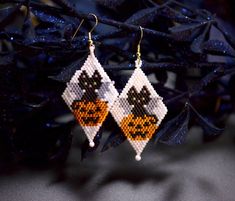 a pair of halloween themed earrings hanging from a tree