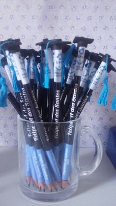 a clear cup filled with blue and black markers on top of a table next to a pen holder