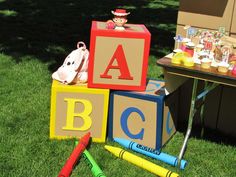 children's abc blocks and crayons are on the grass near a table with toys