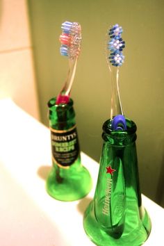 two toothbrushes are in a green glass bottle