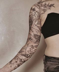 a woman's arm with flowers and leaves tattooed on her left arm, in front of a white background