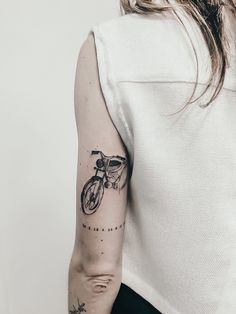 a woman with a bike tattoo on her left arm and right arm behind her back