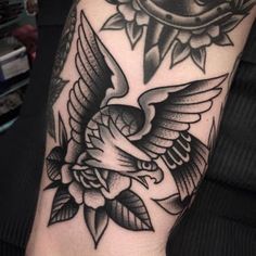 a black and white photo of a bird with roses on it's arm,