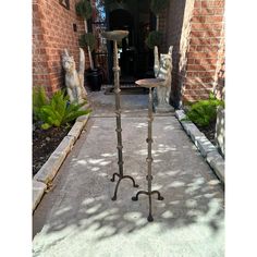 two wrought iron candlesticks stand in front of a brick building