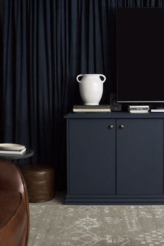 a flat screen tv sitting on top of a blue cabinet next to a brown chair