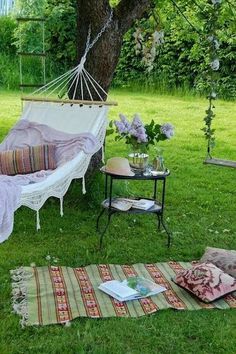 a white hammock sitting on top of a lush green field next to a table