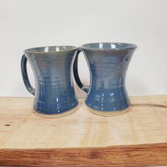 two blue mugs sitting on top of a wooden table