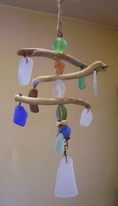 a wind chime hanging from a tree branch with sea glass beads and seashells