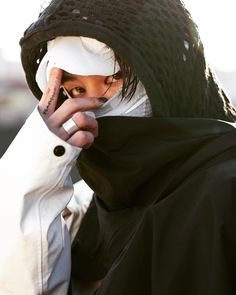 a man in a black and white outfit talking on a cell phone while holding his hand to his face