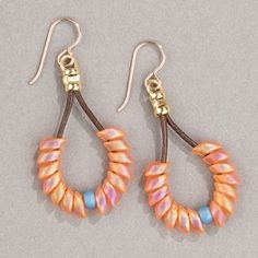 two pairs of earrings with beads hanging from them on a gray surface, one is orange and the other is blue