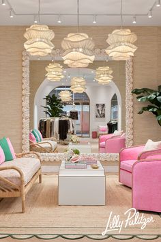 a living room filled with pink furniture and lots of lights hanging from the ceiling above