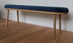 a wooden bench sitting on top of a hard wood floor next to a white wall