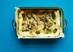 a casserole dish with broccoli and cheese in it on a blue background