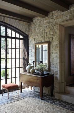 a living room filled with furniture and windows next to a stone wall on top of a floor