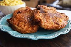 two fried meat patties on a blue plate with macaroni and cheese in the background