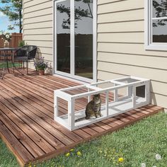 a cat sitting on top of a wooden deck next to a patio with sliding glass doors