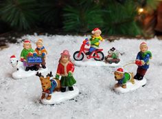 a group of figurines sitting on top of snow next to a christmas tree