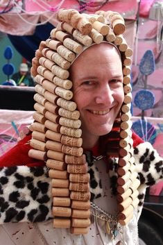 a man wearing a costume made out of wine corks and wooden dowels smiles at the camera