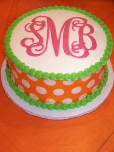 the cake is decorated with green and orange polka dots, and has a monogram on it