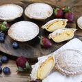 several different types of pastries on a wooden plate with berries and strawberries around them