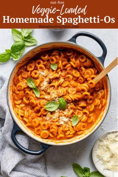 a large pot filled with pasta and basil leaves on top of a white countertop