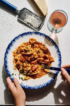 a person holding a fork in a bowl of pasta