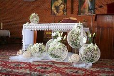 some white flowers are sitting in vases on the floor next to a church alter