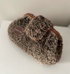 a brown knitted purse sitting on top of a white table next to a wall