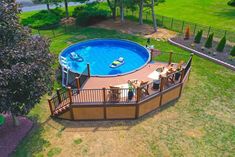 an aerial view of a swimming pool and deck in the middle of a grassy area