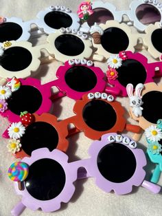 several pairs of children's sunglasses with flowers and bunny faces on them, all in different colors