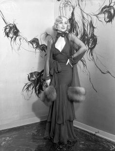 a woman standing in front of a wall with feathers on it