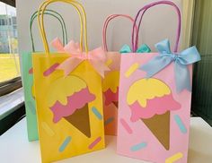 three paper bags with ice cream designs on them, one is pink and the other is yellow