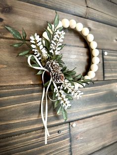 a wreath with white flowers and greenery hanging on a wall