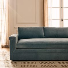 a blue couch sitting on top of a hard wood floor next to a white wall