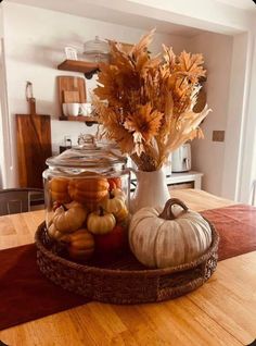 a table topped with a glass jar filled with lots of different types of pumpkins