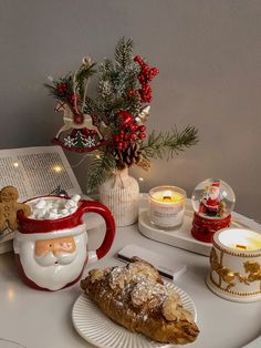 a white table topped with plates and cups filled with food next to christmas decorations on top of a book