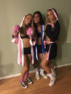 three girls in costumes standing next to each other with boxing gloves on their hands and one girl wearing a pink hoodie