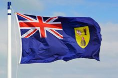 a flag flying in the wind on top of a blue sky with clouds behind it