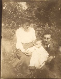 an old photo of a man and woman holding a baby